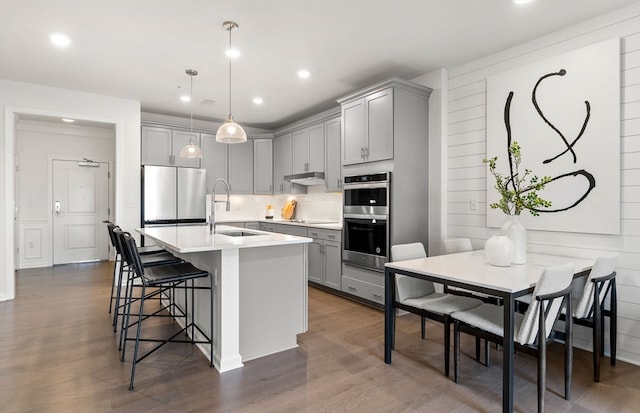 kitchen with dark wood-type flooring, sink, gray cabinets, decorative light fixtures, and stainless steel appliances