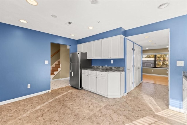 kitchen featuring stainless steel fridge and white cabinets