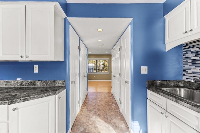 kitchen with tasteful backsplash, sink, white cabinets, and dark stone counters