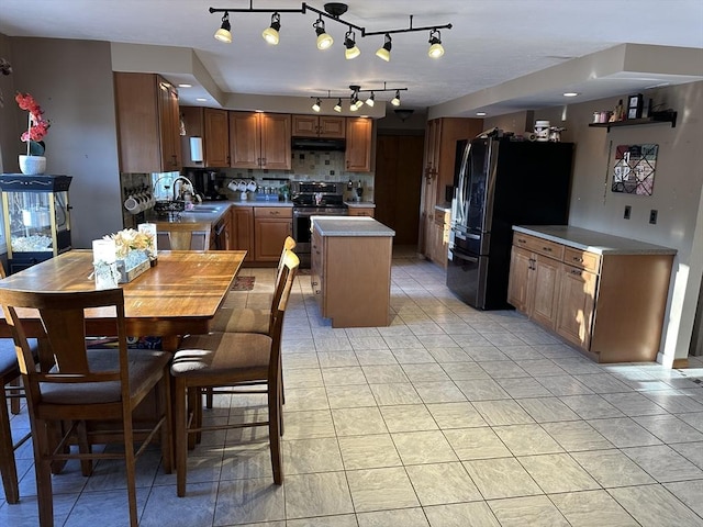 kitchen featuring sink, backsplash, a kitchen island, stainless steel appliances, and light tile patterned flooring