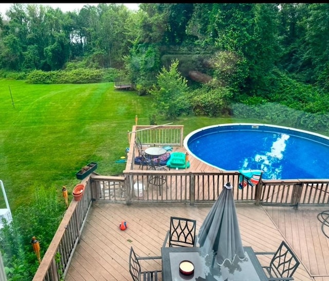 view of pool with a wooden deck and a lawn