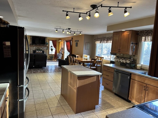 kitchen with sink, light tile patterned floors, a center island, black appliances, and decorative backsplash