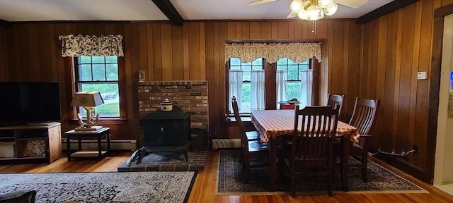 293 Cocasset St, Foxboro, MA 02035 - dining room featuring a wood stove, wood finished floors, a ceiling fan, a baseboard radiator, and wood walls