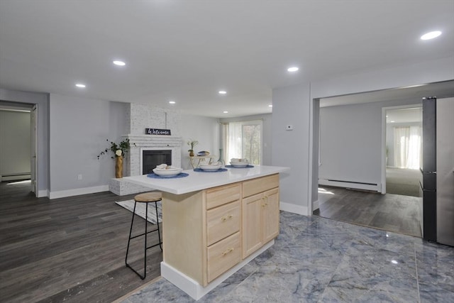 kitchen featuring light brown cabinetry, recessed lighting, and baseboard heating