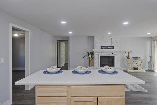kitchen featuring light brown cabinets, open floor plan, baseboards, and a fireplace