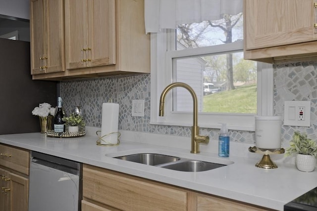 kitchen featuring stainless steel dishwasher, tasteful backsplash, a sink, and light countertops