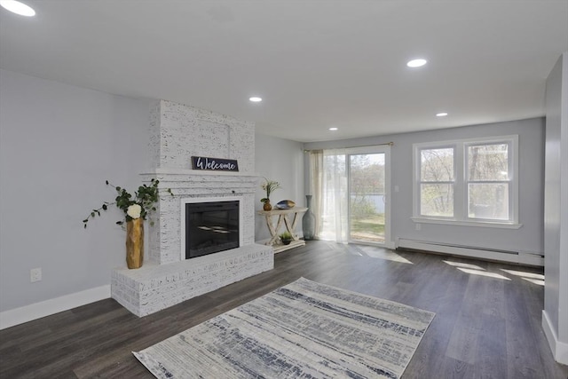 living area with wood finished floors, recessed lighting, a baseboard heating unit, and a fireplace