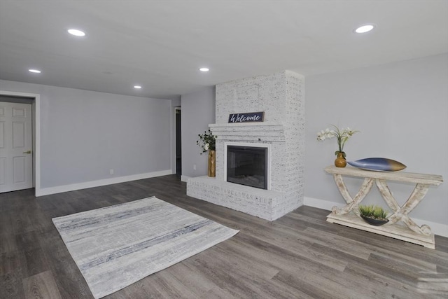 living area with baseboards, a brick fireplace, recessed lighting, and wood finished floors