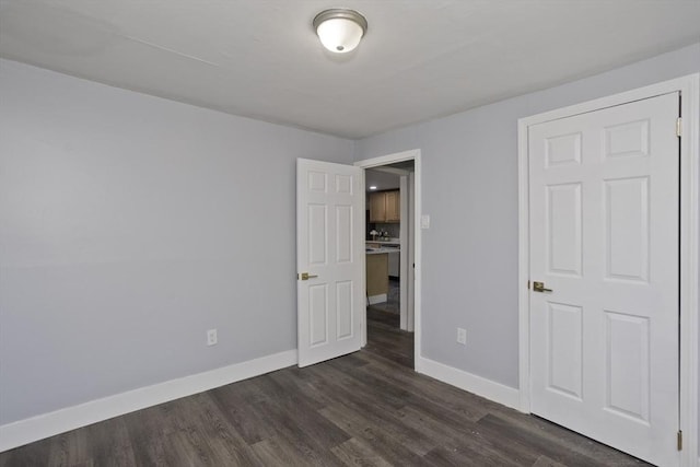 unfurnished bedroom featuring baseboards and dark wood-type flooring