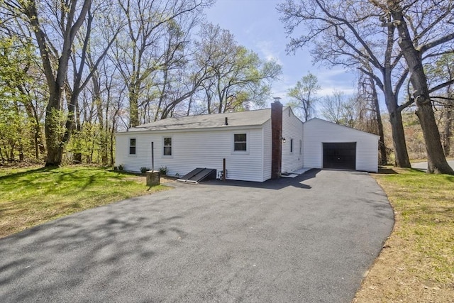 exterior space with a detached garage, a yard, a chimney, and an outdoor structure