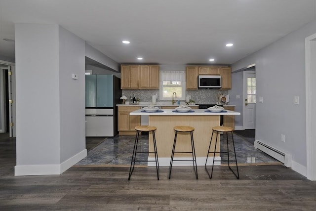 kitchen featuring freestanding refrigerator, white microwave, a center island, light countertops, and a baseboard radiator