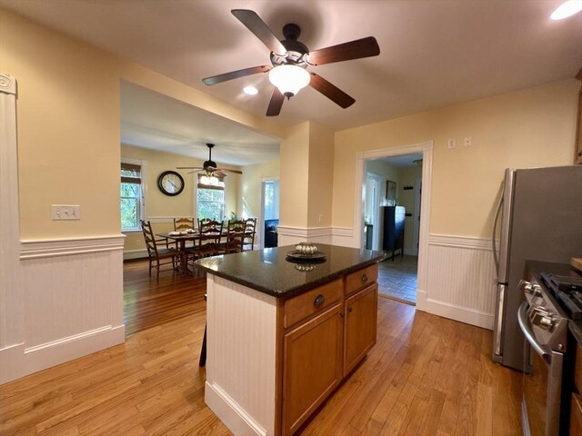 36-1/2 Pearl St Unit 36H, Milford, MA 01757 - kitchen with stainless steel gas stove, a wainscoted wall, ceiling fan, light wood-type flooring, and dark countertops