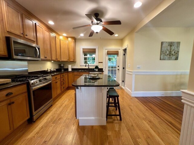 36-1/2 Pearl St Unit 36H, Milford, MA 01757 - kitchen with appliances with stainless steel finishes, a breakfast bar area, light wood-style flooring, a ceiling fan, and brown cabinets