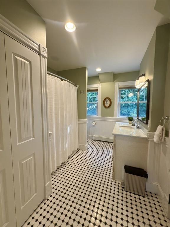 36-1/2 Pearl St Unit 36H, Milford, MA 01757 - bathroom with vanity, wainscoting, a baseboard radiator, a shower with shower curtain, and a decorative wall