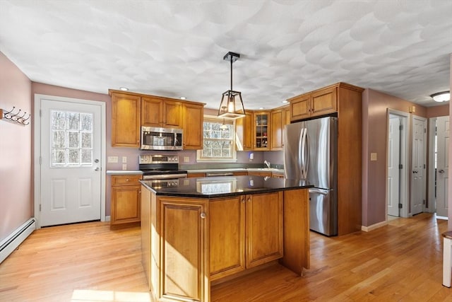 kitchen featuring light wood-type flooring, brown cabinets, a kitchen island, appliances with stainless steel finishes, and glass insert cabinets