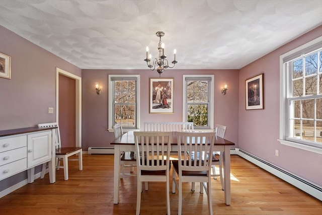 dining space with a baseboard heating unit, light wood-style floors, and a notable chandelier