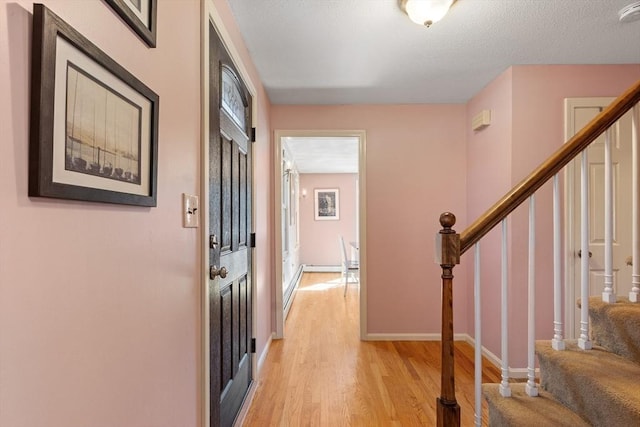 foyer entrance with stairway, light wood-style flooring, and baseboards