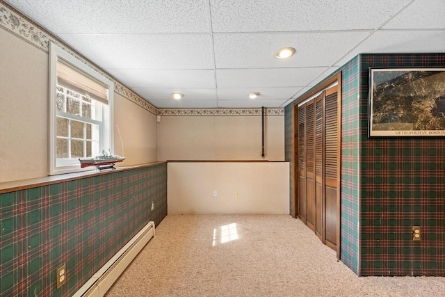 empty room featuring carpet flooring, a paneled ceiling, and baseboard heating