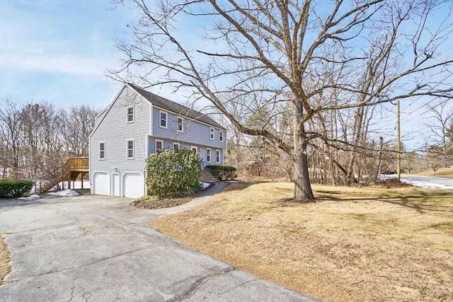 view of property exterior with an attached garage, stairs, and driveway