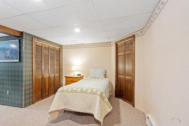 carpeted bedroom featuring a closet, baseboard heating, and a paneled ceiling