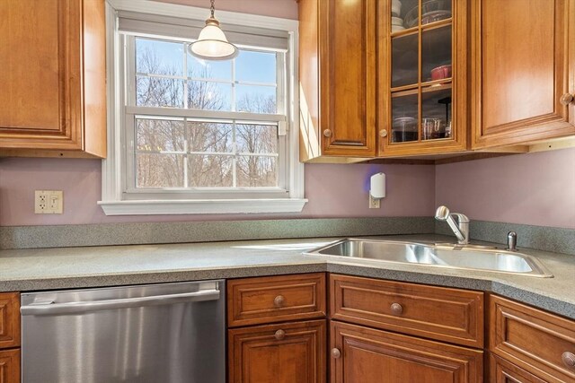 kitchen with brown cabinetry, dishwasher, glass insert cabinets, and a sink