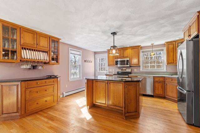 kitchen with baseboard heating, brown cabinets, appliances with stainless steel finishes, and a center island