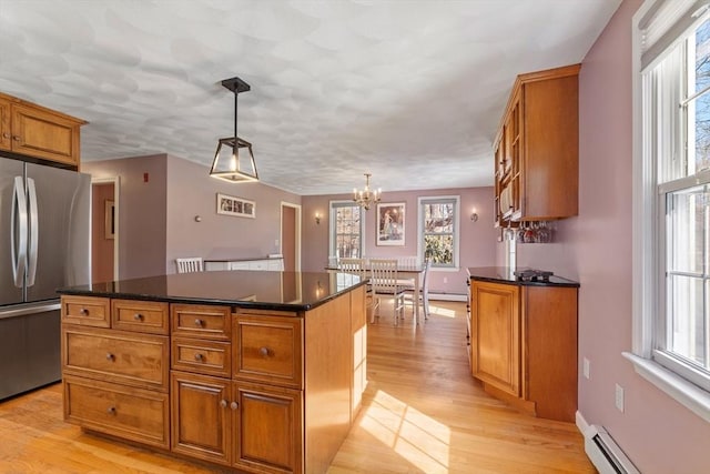 kitchen featuring light wood finished floors, a kitchen island, freestanding refrigerator, brown cabinetry, and a baseboard radiator