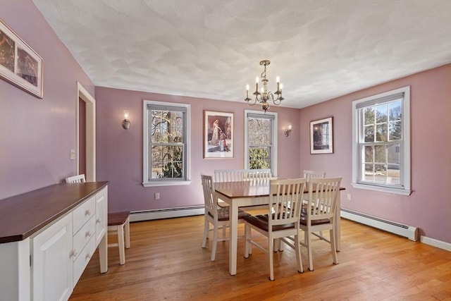 dining room with light wood finished floors, baseboards, a baseboard heating unit, and an inviting chandelier