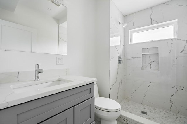 bathroom featuring tiled shower, vanity, and toilet