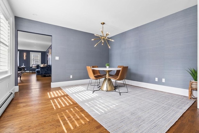 dining space featuring a chandelier, baseboards, a wealth of natural light, wood finished floors, and a baseboard radiator