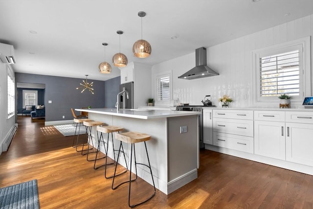 kitchen featuring wall chimney range hood, appliances with stainless steel finishes, dark wood-type flooring, and a baseboard radiator