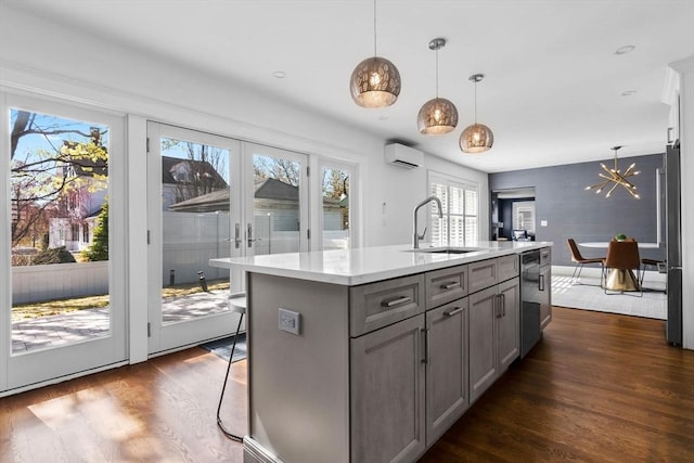 kitchen featuring dark wood-style flooring, a wall mounted AC, a sink, dishwasher, and gray cabinetry