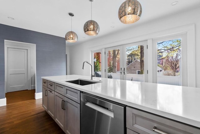 kitchen featuring a sink, light countertops, dark wood-type flooring, stainless steel dishwasher, and gray cabinetry