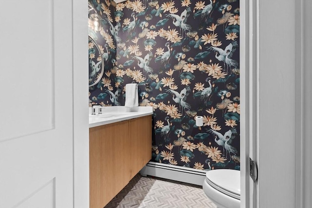 half bath with vanity, baseboards, baseboard heating, and toilet