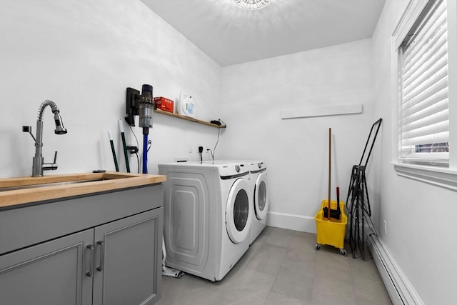clothes washing area with cabinet space, a sink, separate washer and dryer, baseboards, and a baseboard radiator
