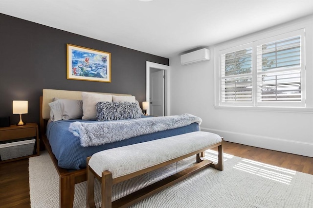 bedroom featuring baseboards, a wall unit AC, and wood finished floors