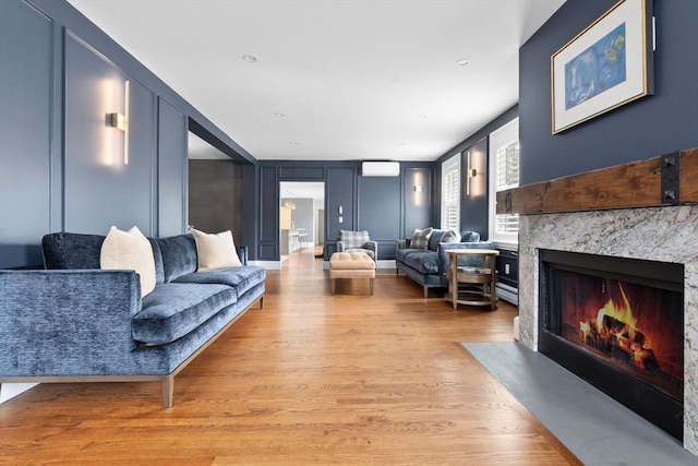 living area with a fireplace, a decorative wall, and light wood-type flooring