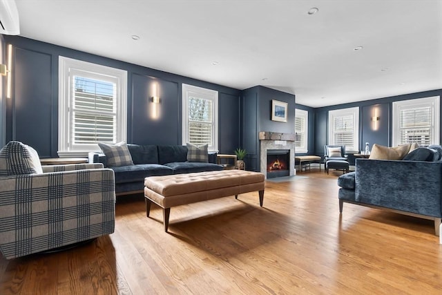 living area with a fireplace with flush hearth, a decorative wall, and light wood finished floors