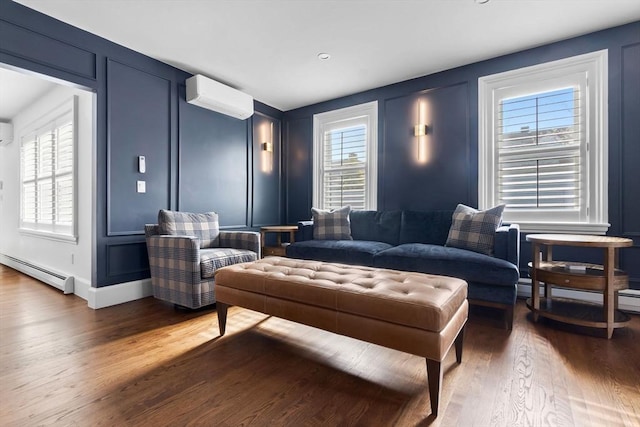 interior space featuring wood finished floors, a wall mounted air conditioner, a decorative wall, and a baseboard heating unit