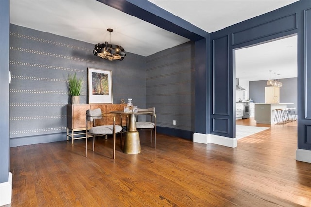 office area featuring a sink, baseboards, wood finished floors, and a chandelier