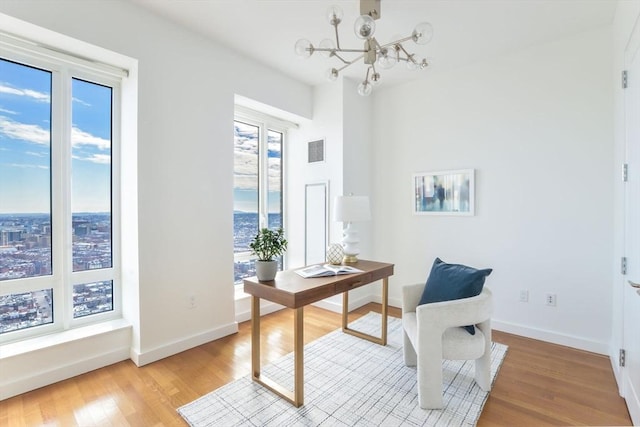 office area featuring visible vents, light wood-style flooring, baseboards, and an inviting chandelier