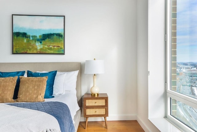 bedroom featuring multiple windows, baseboards, and wood finished floors