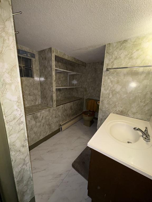 18 Gordon St, Worcester, MA 01604 - full bath with a textured ceiling, vanity, baseboard heating, marble look tile flooring, and a shower