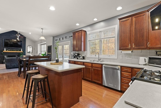 kitchen with decorative backsplash, stainless steel appliances, sink, hanging light fixtures, and lofted ceiling