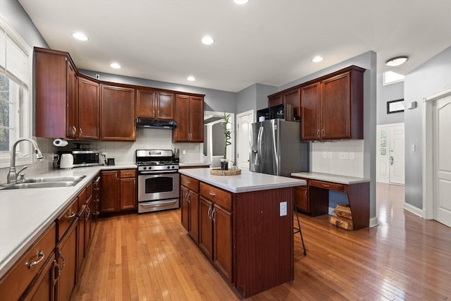 kitchen with sink, a center island, stainless steel appliances, a kitchen breakfast bar, and light hardwood / wood-style floors