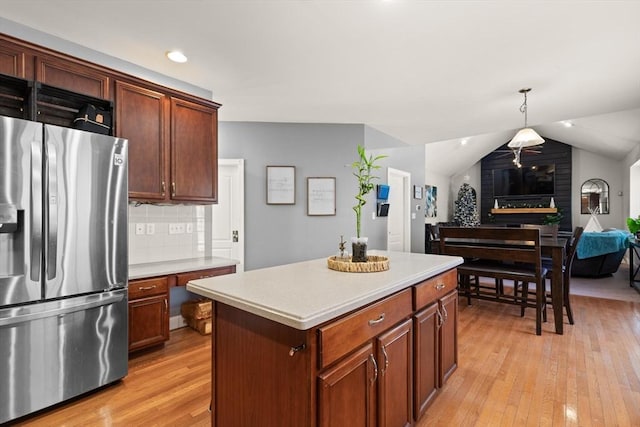 kitchen with pendant lighting, a center island, stainless steel refrigerator with ice dispenser, vaulted ceiling, and tasteful backsplash