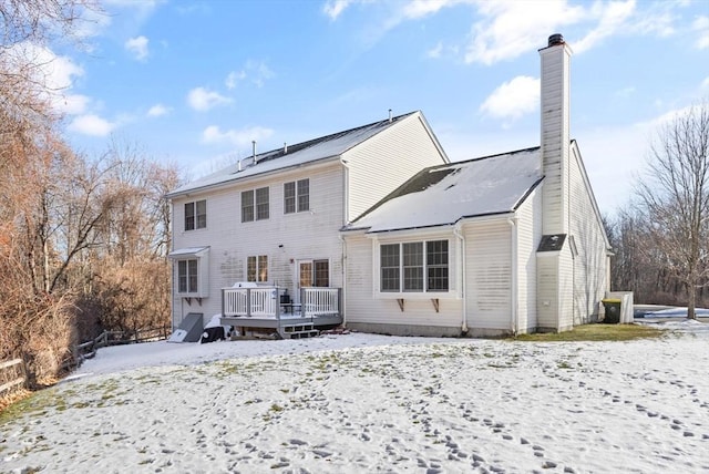 snow covered rear of property with a deck