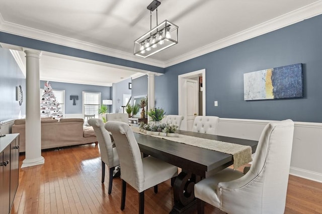 dining room with hardwood / wood-style flooring, ornamental molding, and decorative columns