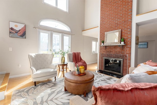 living room with a fireplace, a high ceiling, and light hardwood / wood-style floors