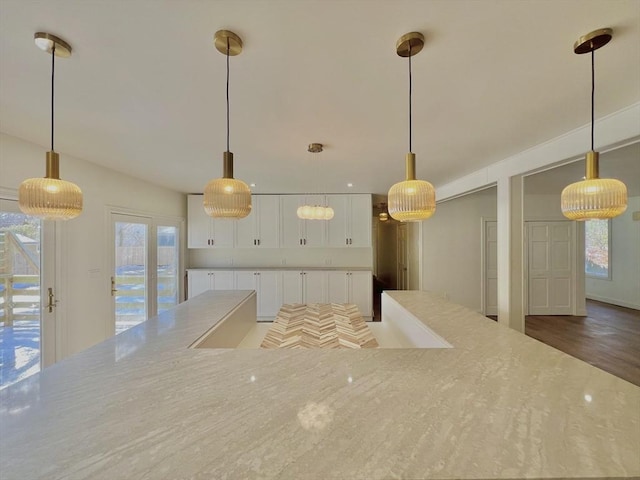 kitchen with hanging light fixtures, white cabinets, and light stone counters